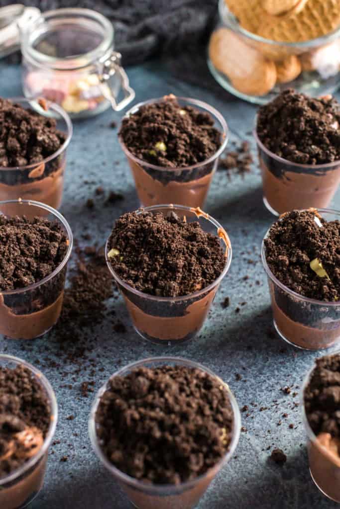 assembling the nine pudding cups by adding the dirt over the pudding. 