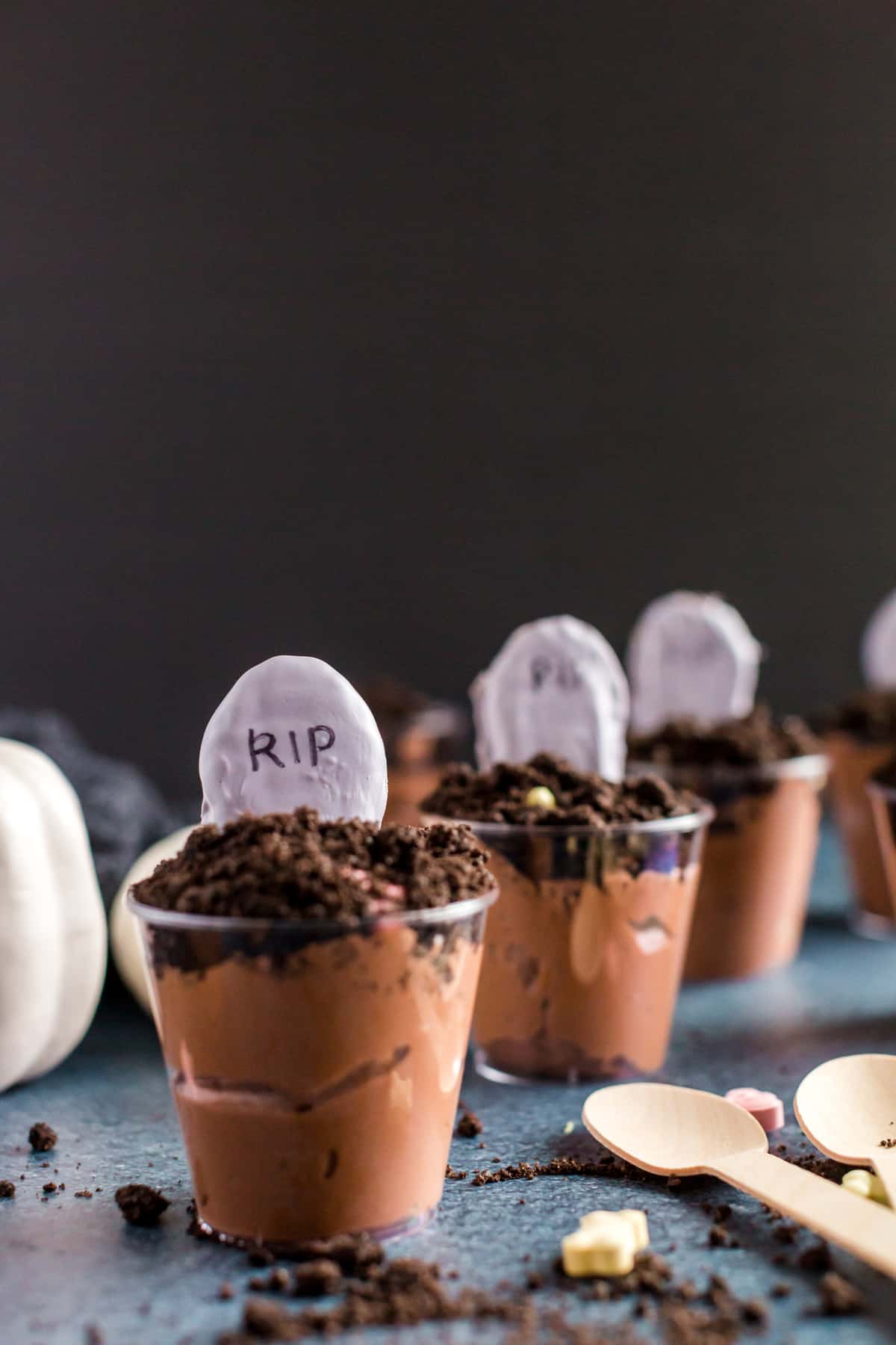 Pudding cups with tombstones on blue table with black background. 