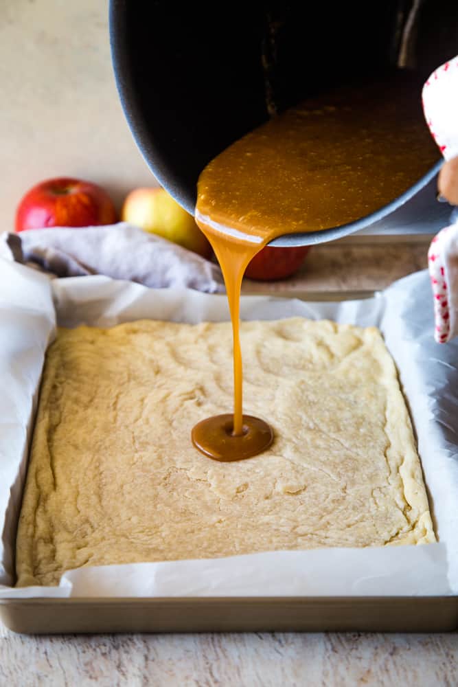 pouring apple caramel recipe into pan over crust