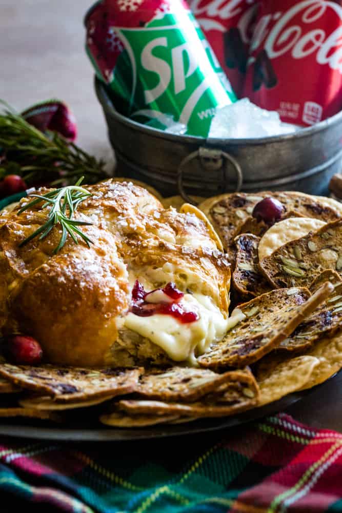 cranberry baked brie on a dish with soda in background