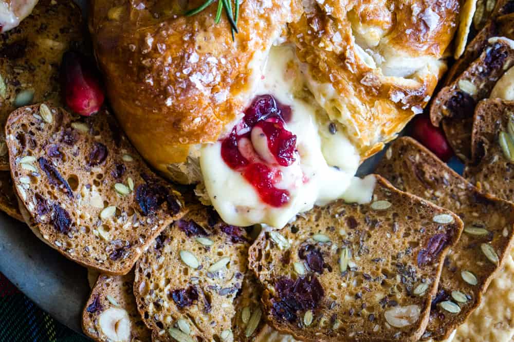 cranberry baked brie on a plate with crackers and melting cheese