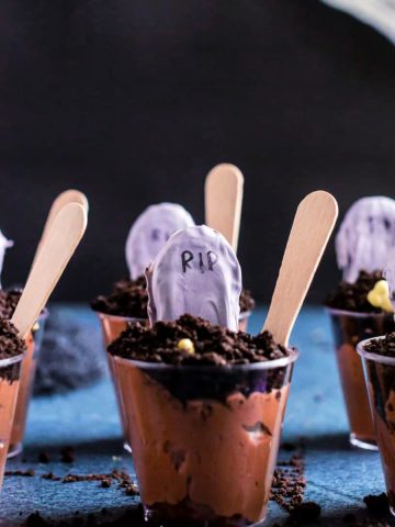 Graveyard pudding cups lined up with a black background.