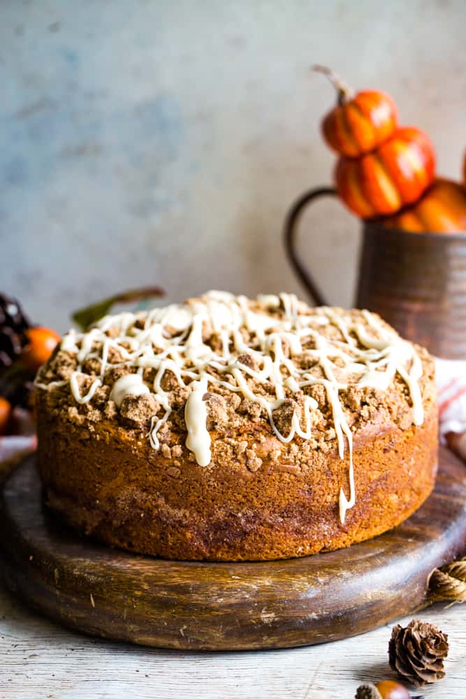 pumpkin coffee cake on wood platter with pumpkins in background