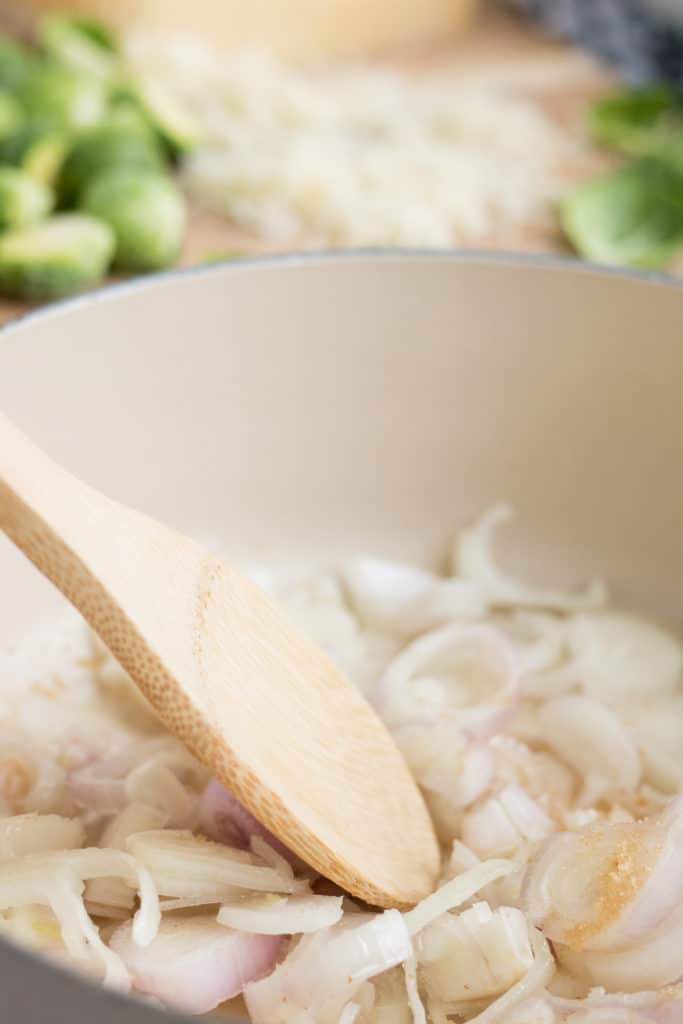 caramelized onions in pan with spoon stirring for brussels sprouts au gratin 