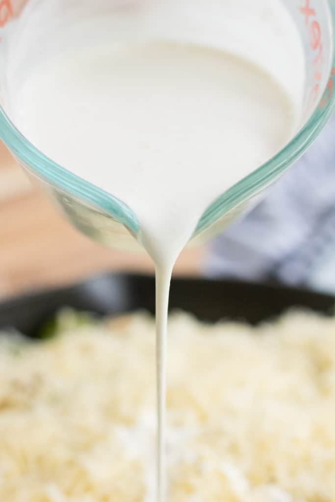 pouring the cream into the brussels sprout cassrole