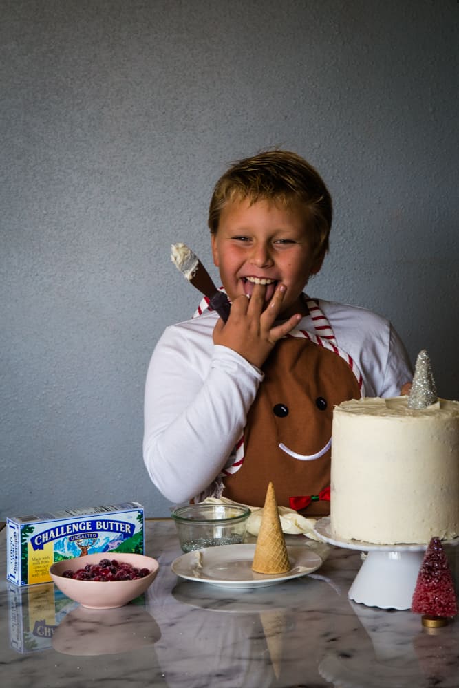 boy eating frosting while decorating cranberry christmas cake