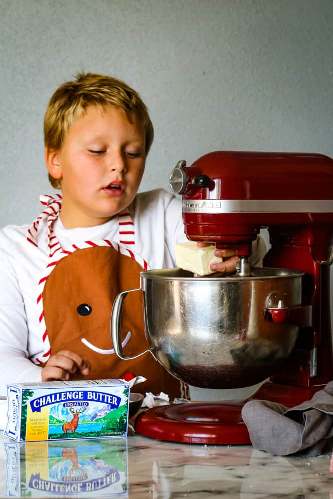 boy putting butter into mixing bowl to make cranberry christmas cake