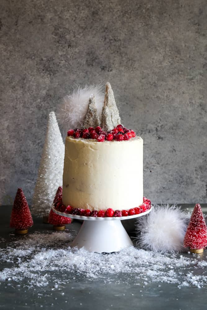 cranberry spice cake on cake stand with trees in background