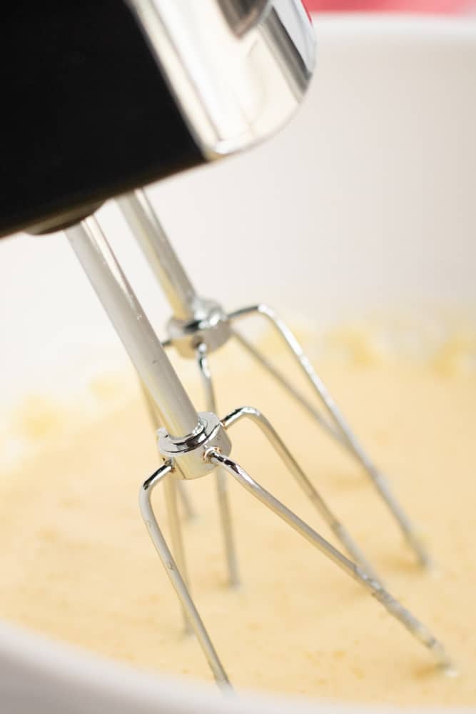 Blending the wet ingredients in white bowl with a hand mixer. 