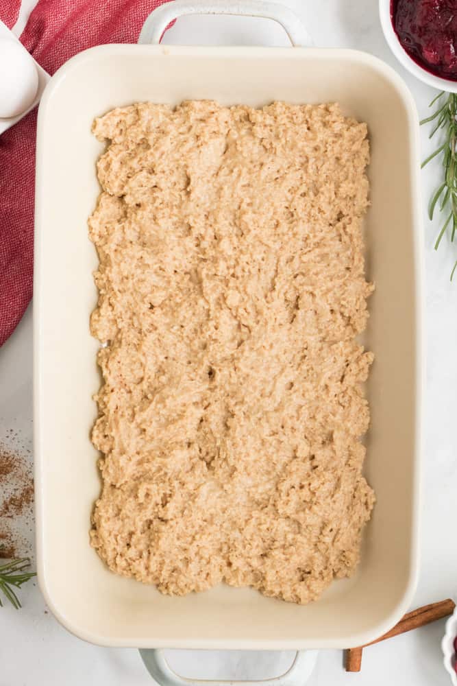 Putting half of the coffee cake batter into the white baking dish. 