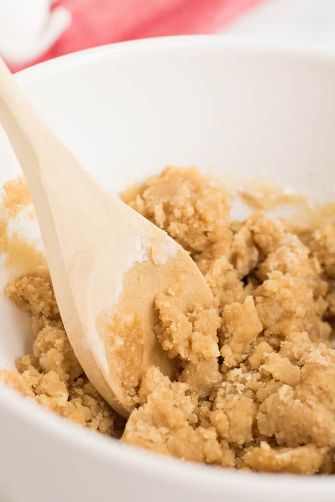 Mixing together the streusel topping with a wooden spoon in small white bowl. 