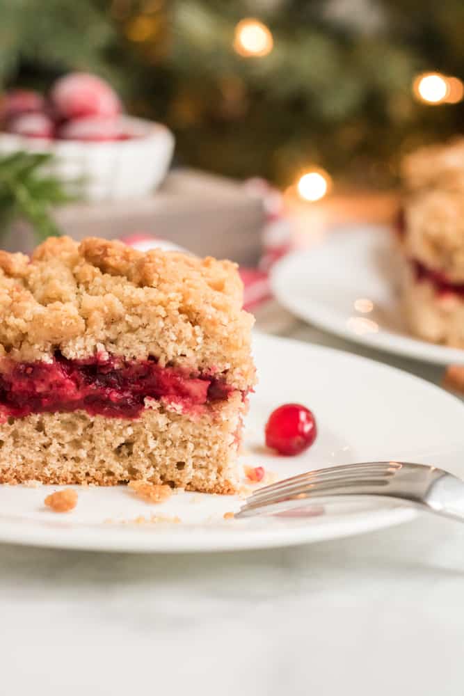 Square slice of coffee cake on white plate with fork next to it. 