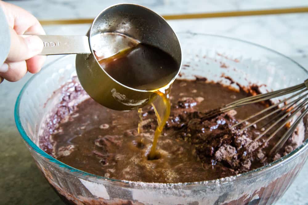 Pouring the hot coffee into the chocolate cake batter in glass bowl. 