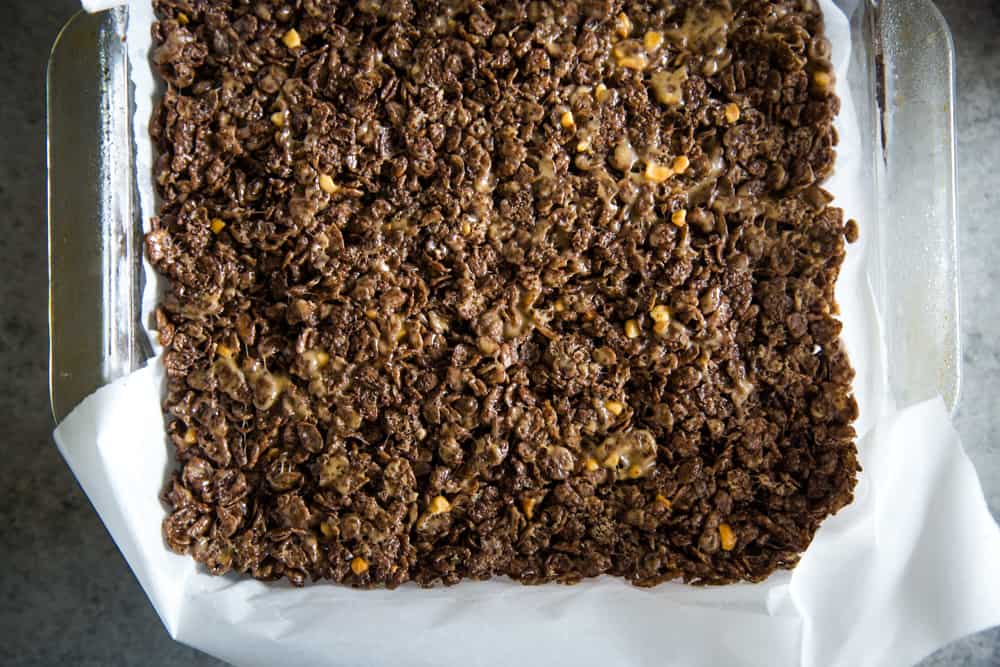 Overhead shot of pressed chocolate peanut butter squares in a square pan. 