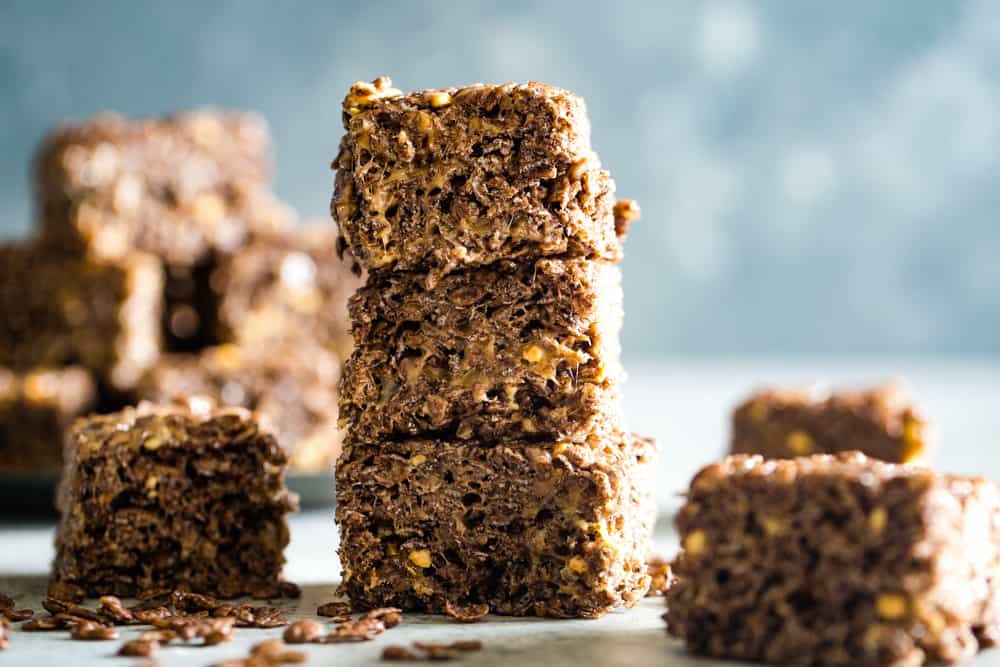 Three stacked chocolate peanut butter squares, with single squares surrounding the stack. 