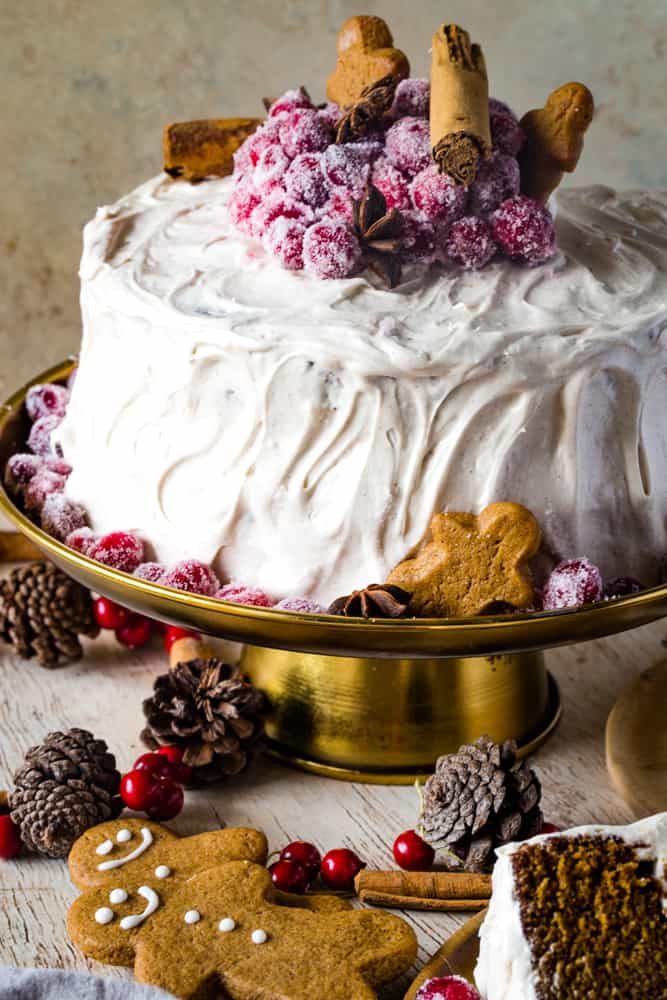 gingerbread layered cake on a gold cake stand with gingerbread men and sugared cranberries. 