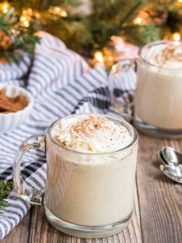 cup of eggnog recipe in two glasses with Christmas tree in background