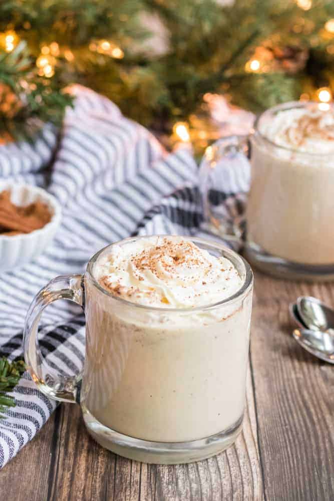 cup of eggnog recipe in two glasses with Christmas tree in background