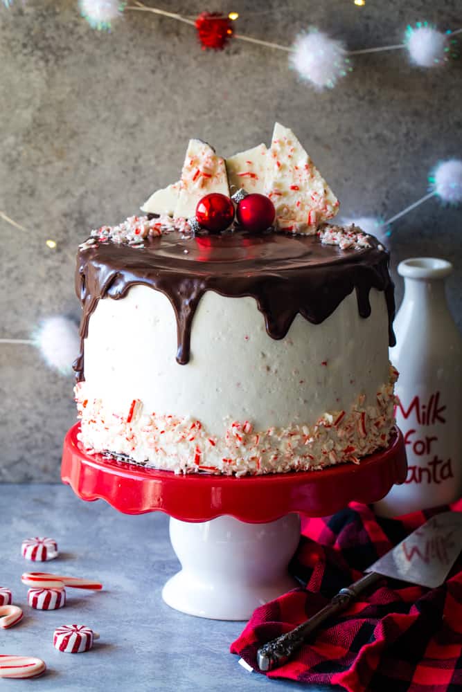 peppermint bark layer cake with chocolate ganache running off the sides and peppermint bark on the top of the cake. 