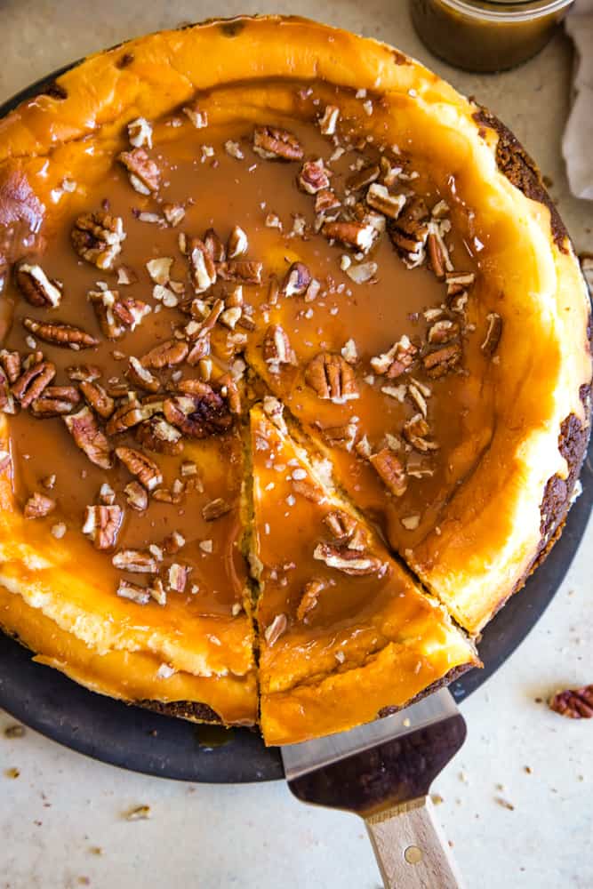 taking a slice of sweet potato swirled cheesecake from the plate with a pie spatula. 