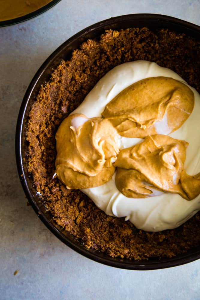 Adding the cheesecake and pie batter to the gingersnap crust to make sweet potato swirled cheesecake. 