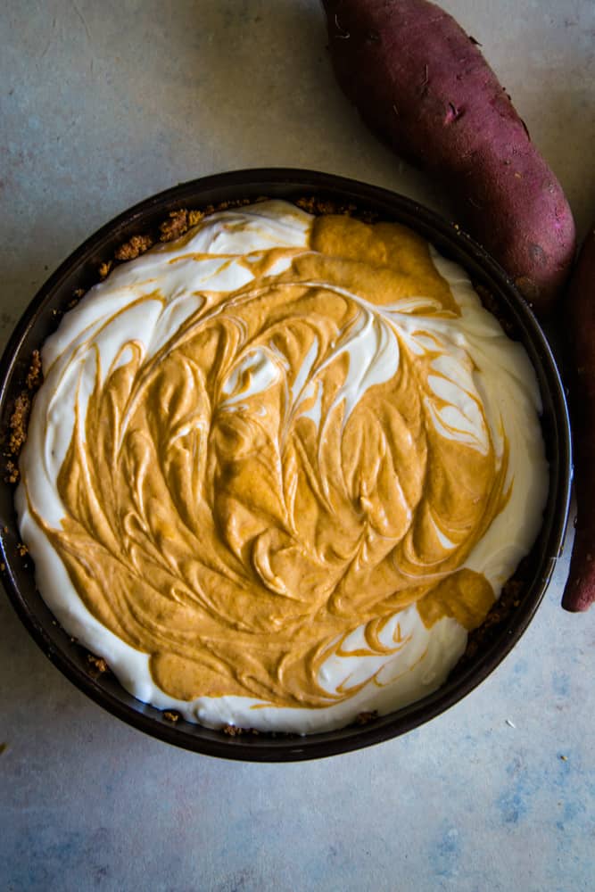 swirling the cheesecake batter and sweet potato pie batter in metal springform pan. 