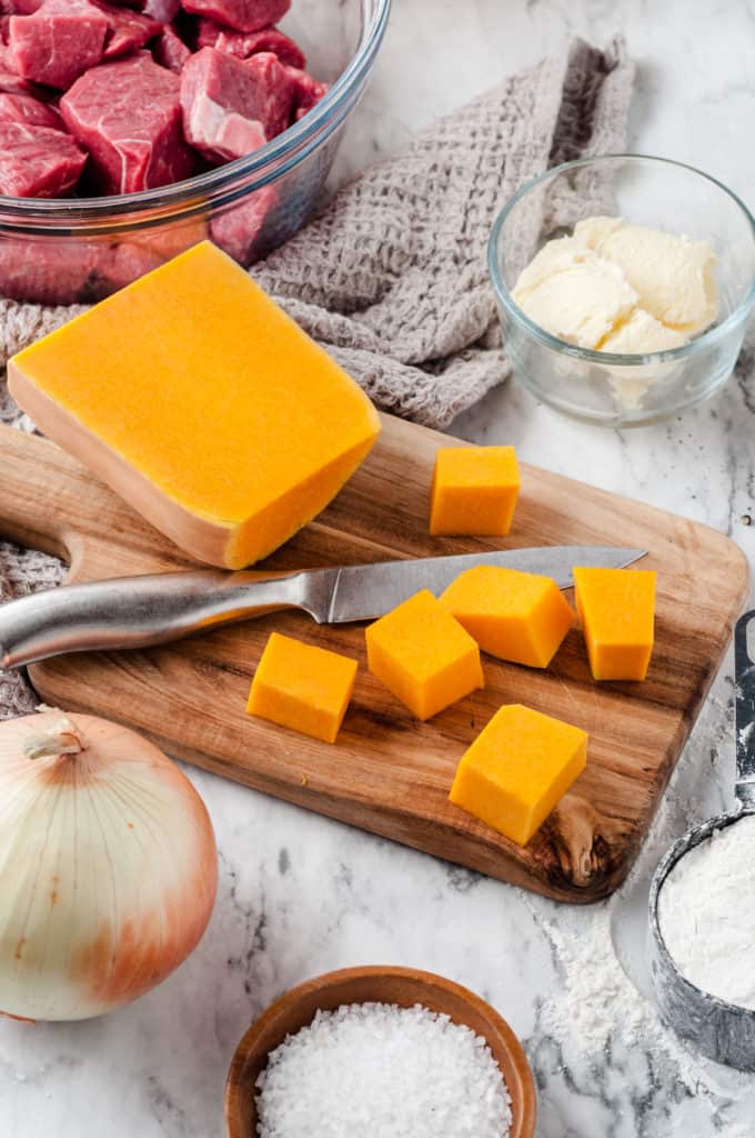 a cutting board with peeled and cubed butternut squash