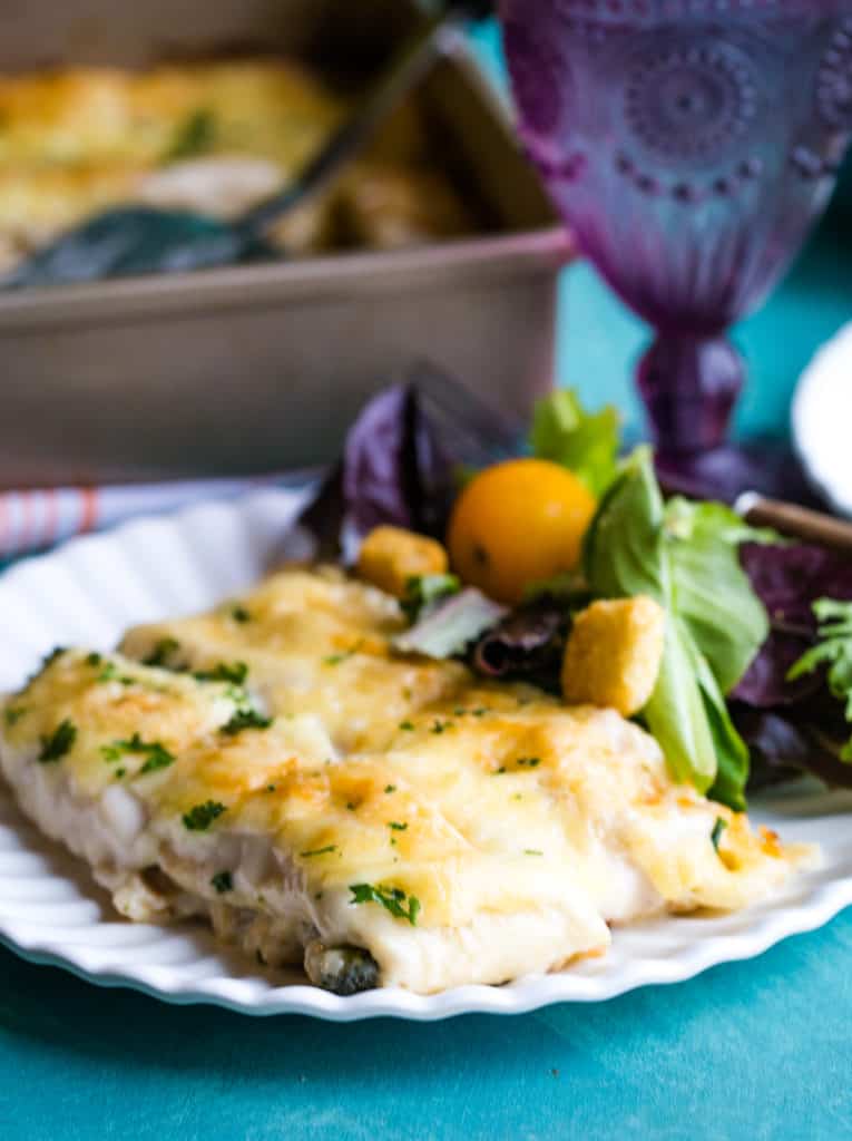 white plate of stuffed crepes with side salad