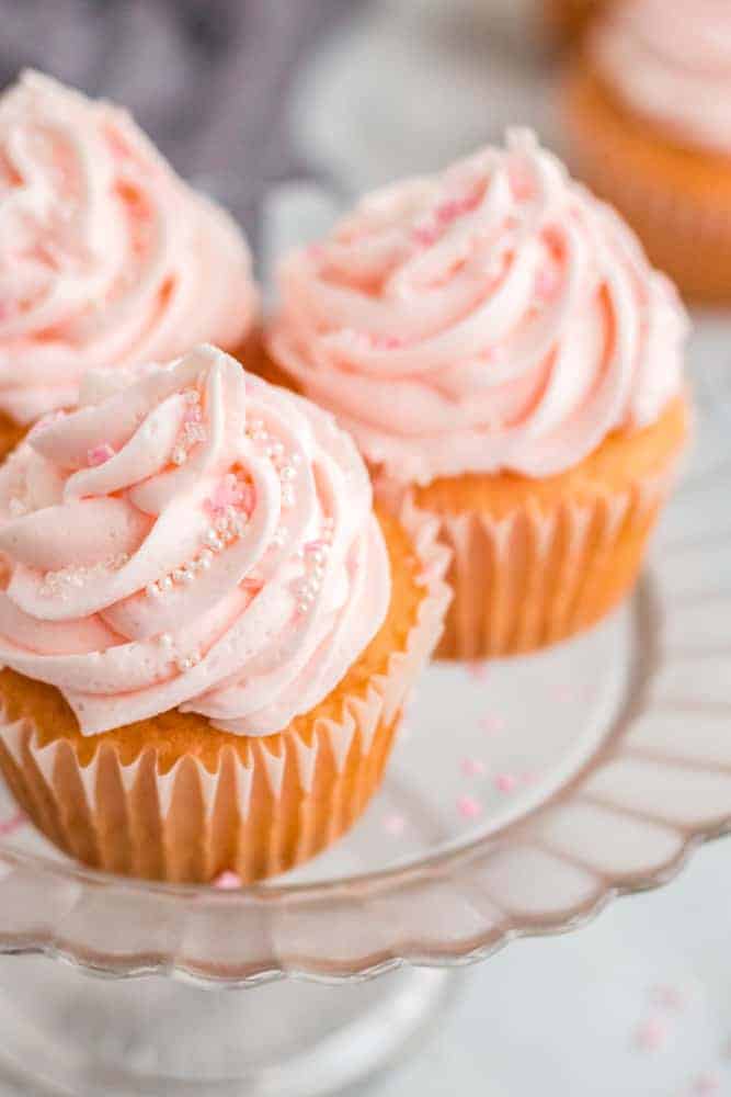 three cupcakes with pink frosting on pink cake plate