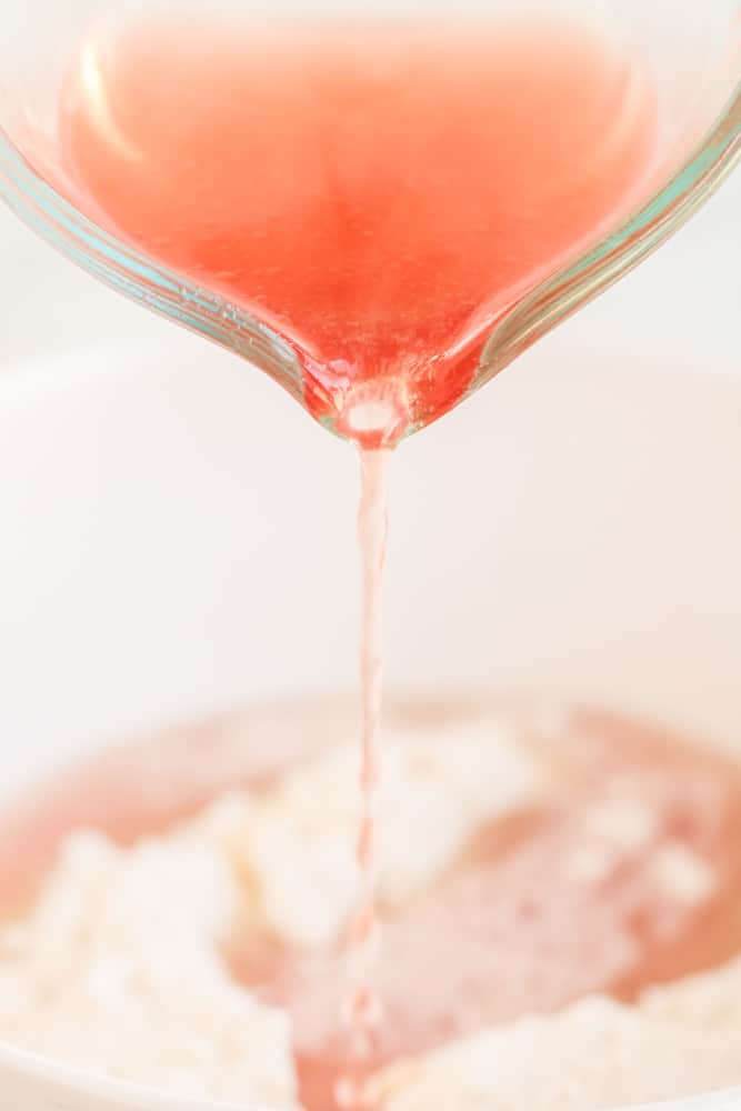 pouring in the pink champagne into cake batter