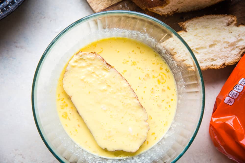 dipping bread into bowl of egg and milk mixture