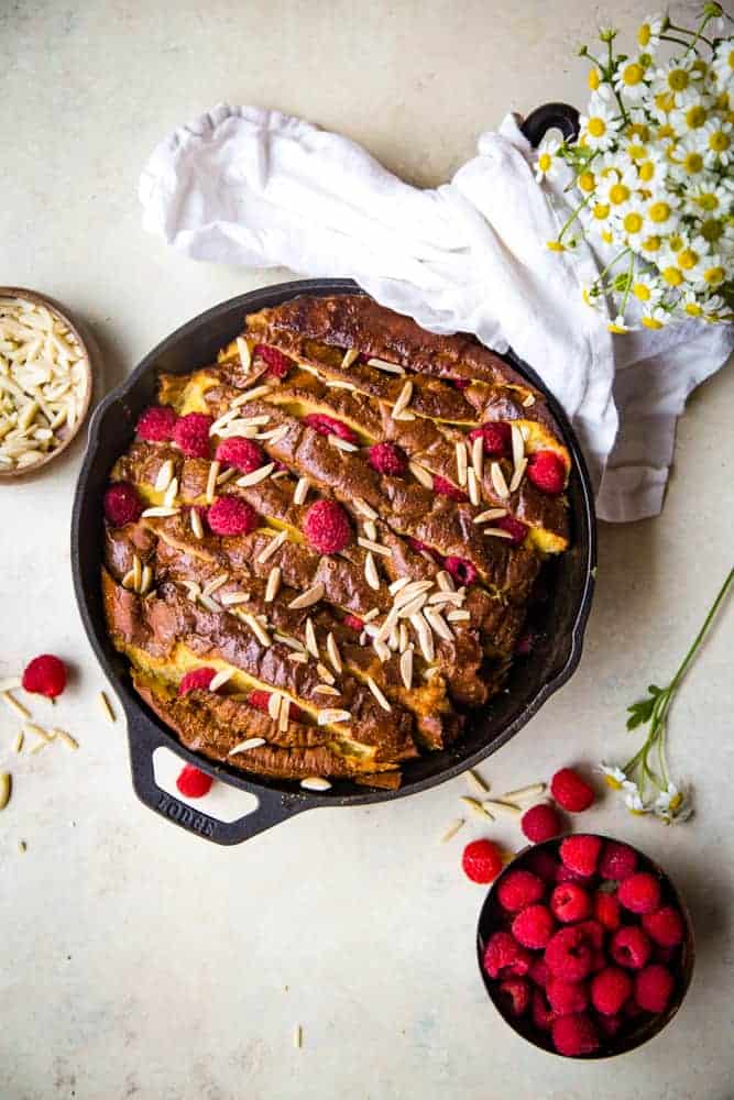 cast iron pan with french toast bread, raspberries, and almonds