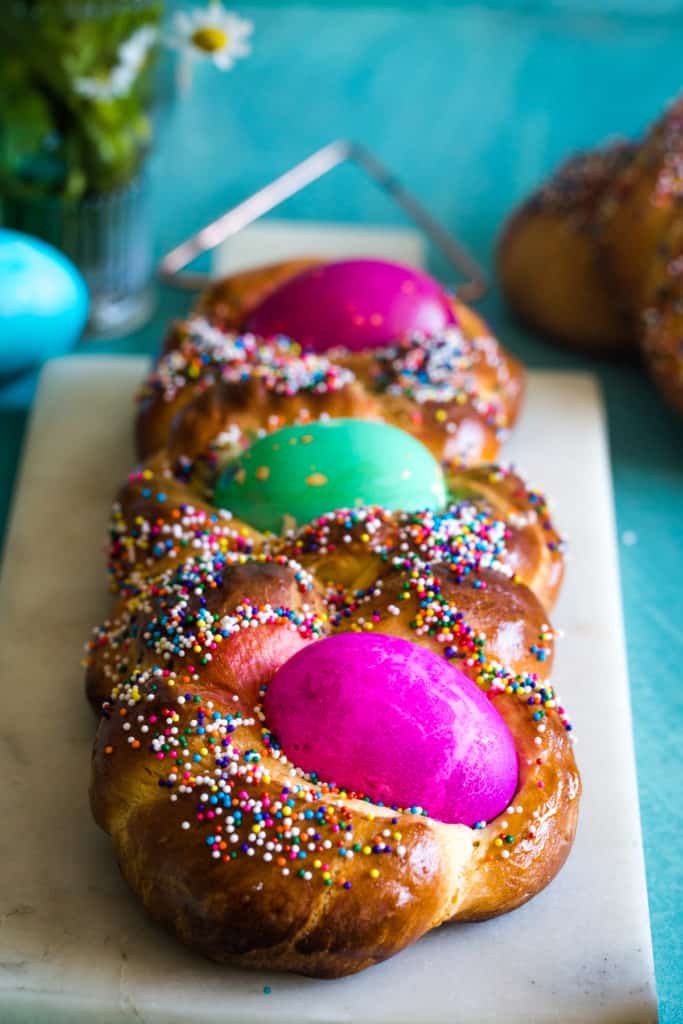 loaf of braided brioche with colored eggs nestled in