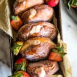 Loaf pan with strawberry custard filled donuts on white marble background