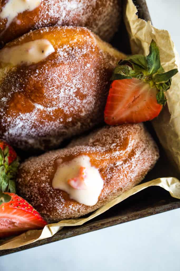 up close photo of strawberry custard filled doughnut in square pan