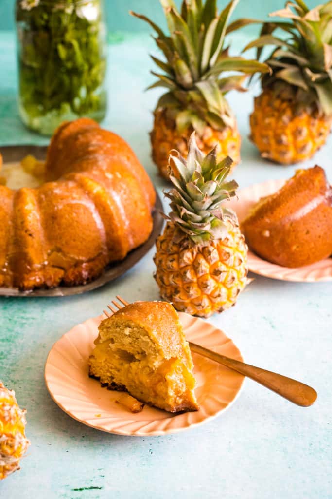 bundt cake slice on pink plate with baby pineapples in the background