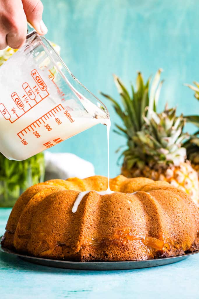 hand pouring glaze over bundt cake