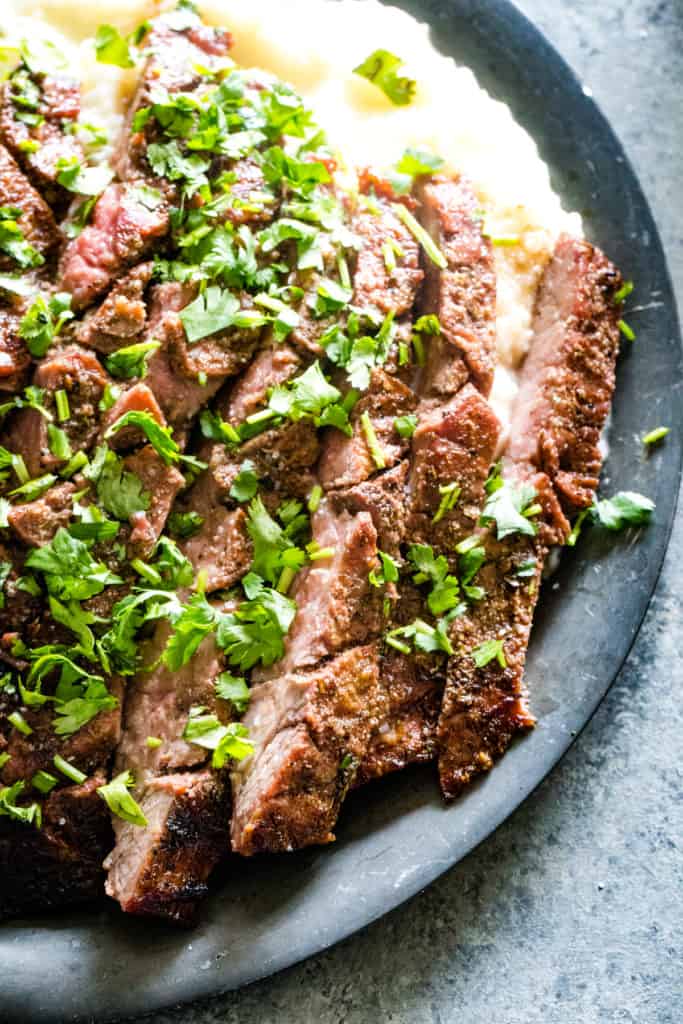 silver plate with grill flank steak slices and mashed potatoes