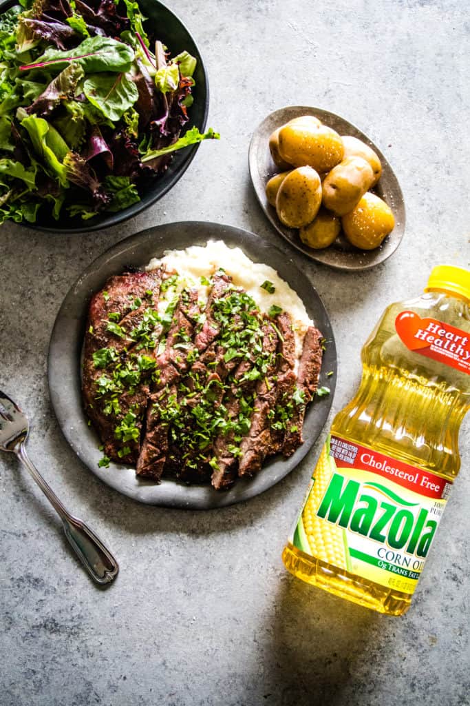 metal plate with grilled flank steak and a bottle of mazola oil