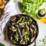 top down shot of cilantro beer broth mussels in cast iron skillet