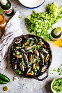 top down shot of cilantro beer broth mussels in cast iron skillet