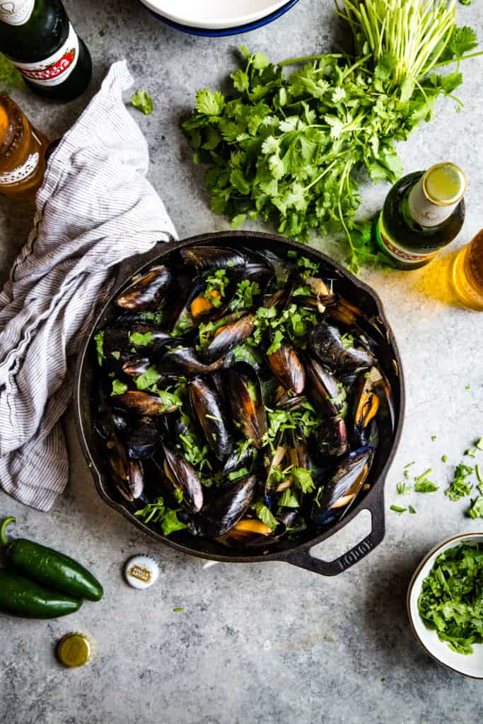 skillet with cooked mussels on metal background