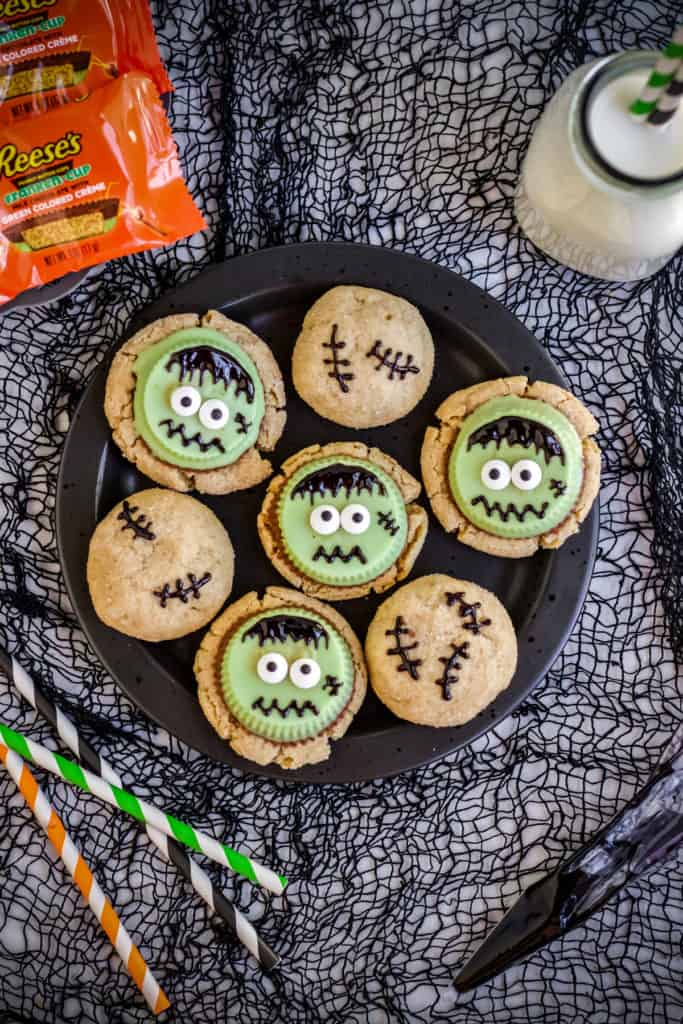 plate of frankenstien cookies on black background and glass of milk