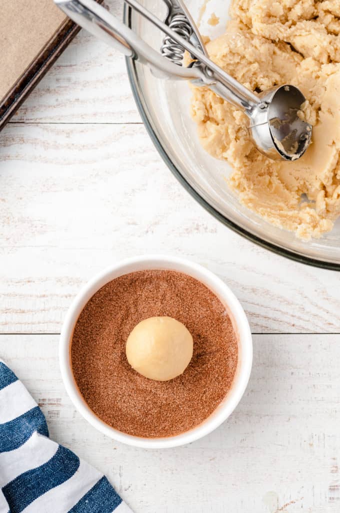 bowl of cinnamon and sugar with cookie dough ball in center 