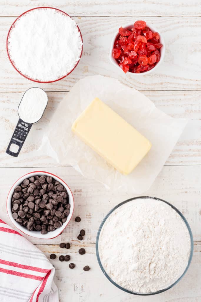 ingredients for chocolate cherry shortbread cookies on white wood background. 