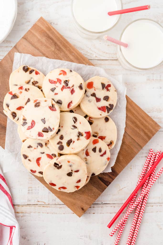 A wood board of dark chocolate cherry cookies on wood cutting board