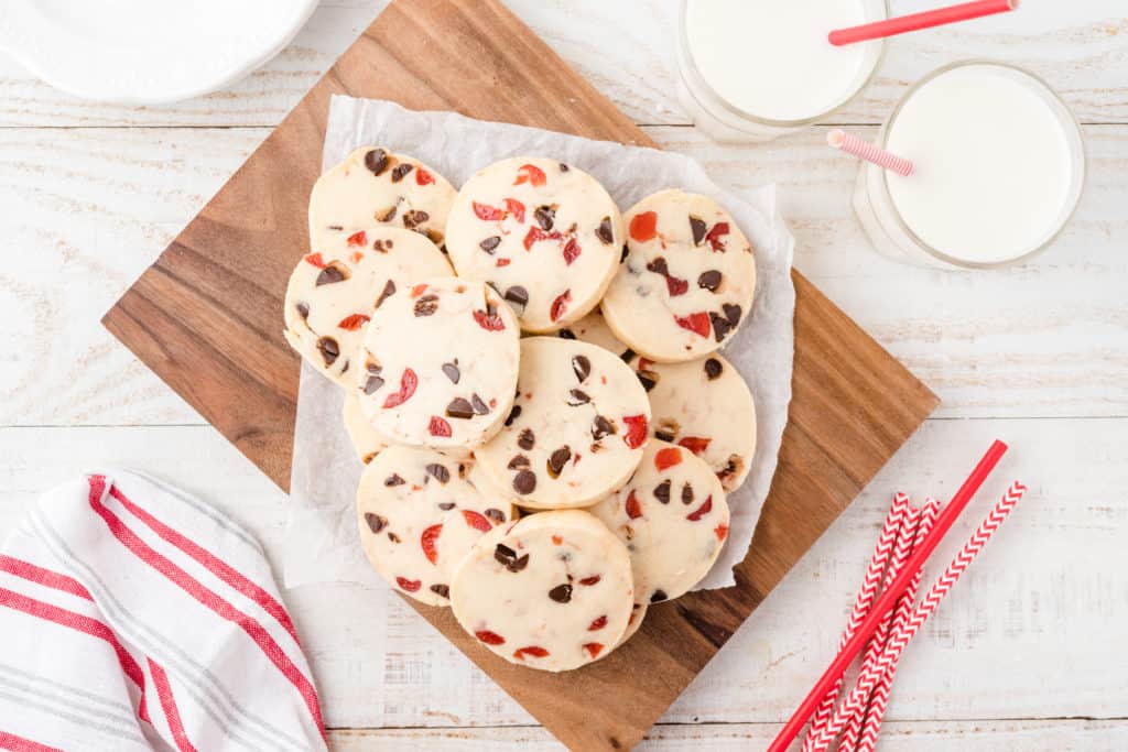 A plate of chocolate cherry shortbread cookies on wood cutting board. 