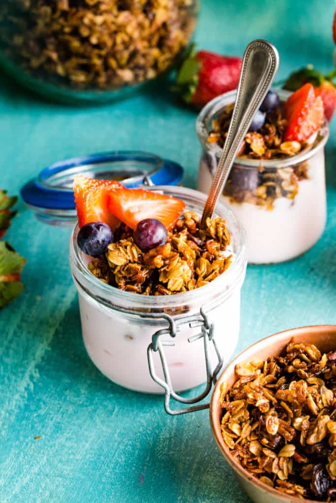 closeup shot of yogurt parfait with fresh berries in a jar with a spoon. 