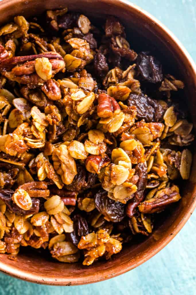 large wood bowl of the cooked homemade granola with raisins and nuts. 