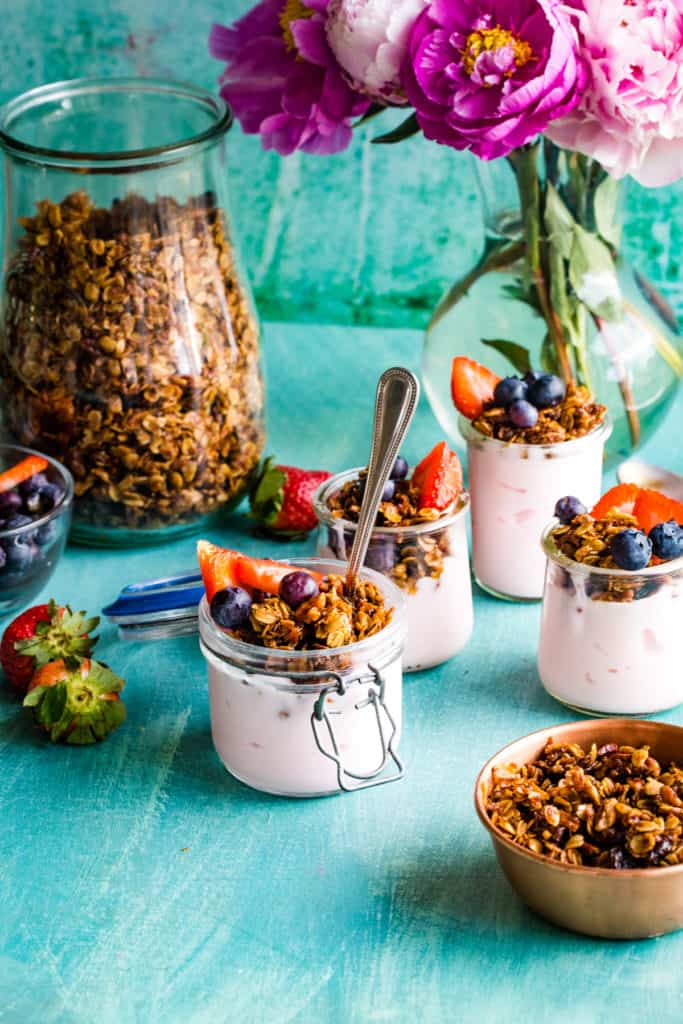 small jars of yogurt parfaits with large jar of granola in background